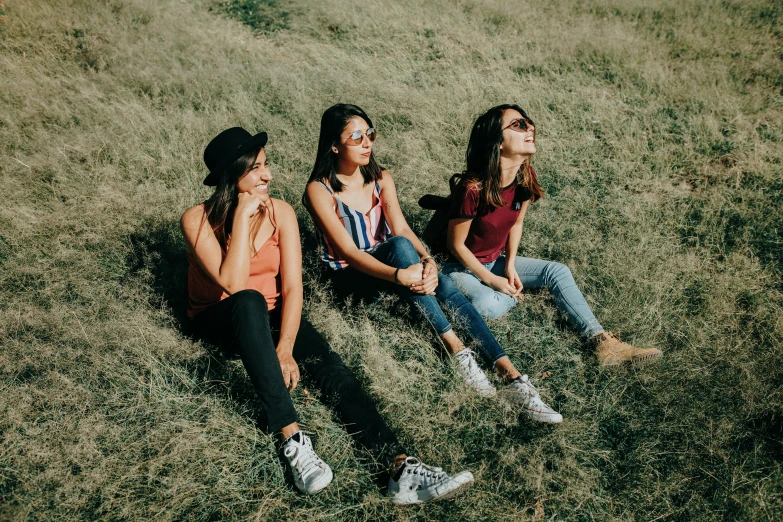 three beautiful women sitting on the grass talking