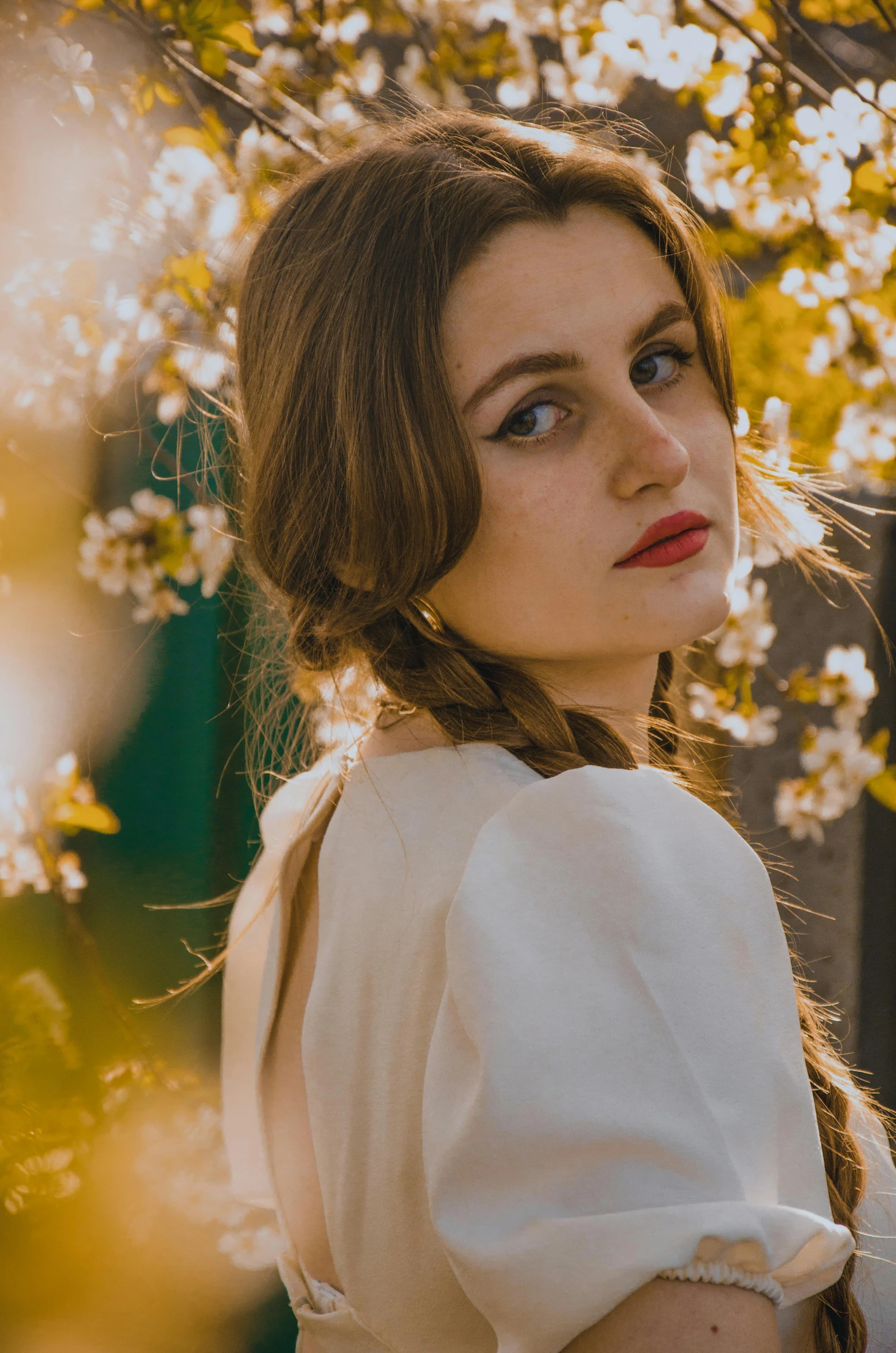 a woman standing in front of a tree with white flowers, inspired by Elsa Bleda, pexels contest winner, renaissance, two pigtails hairstyle, portrait of young woman, (golden hour), center parted brown hair