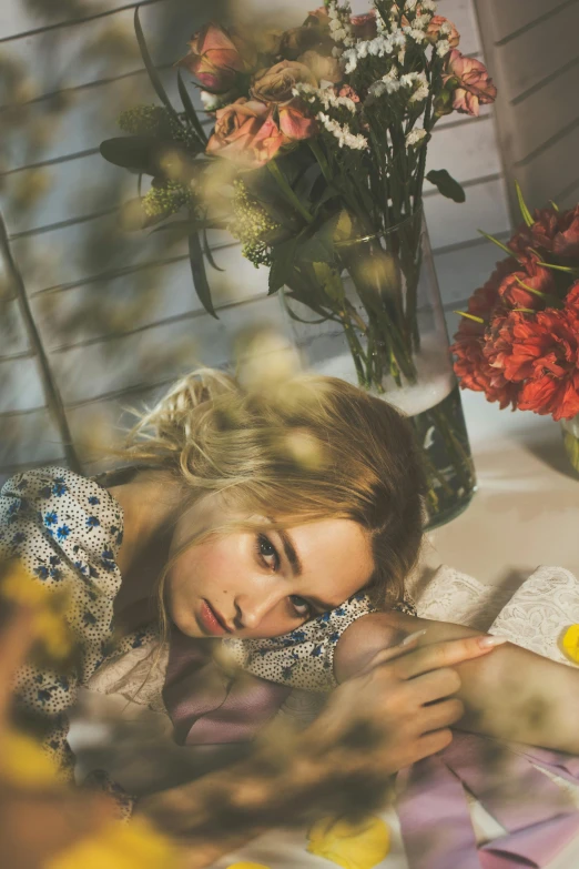 a woman laying on top of a bed next to flowers, a picture, inspired by Elsa Bleda, trending on pexels, photorealism, portrait of annasophia robb, kiko mizuhara, thoughtful ), a blond