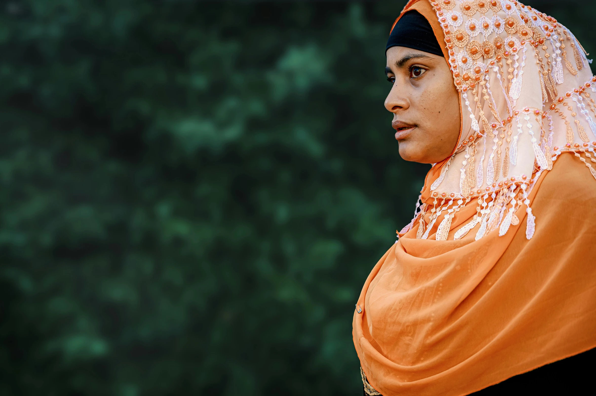 a close up of a person wearing a headscarf, by Matija Jama, pexels contest winner, hurufiyya, orange and black, an arab standing watching over, at a park, ethnic group