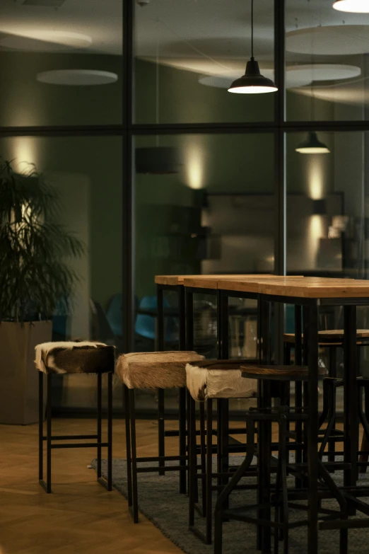 four brown stools are against a glass wall