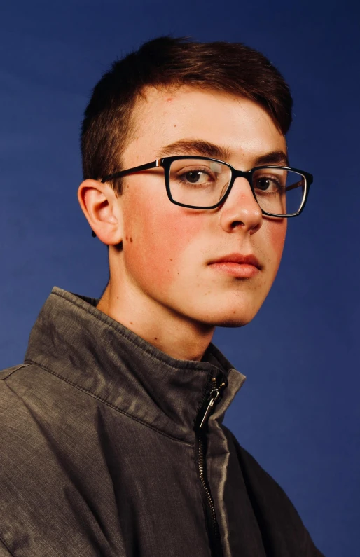 a boy with glasses is wearing a grey jacket