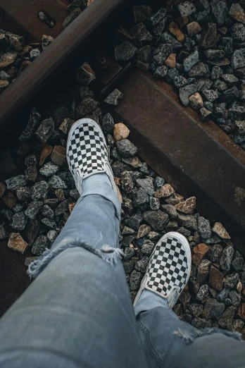 a person standing on top of a train track, unsplash contest winner, visual art, on a checkered floor, whole shoe is in picture, wearing casual clothing, sitting on temple stairs
