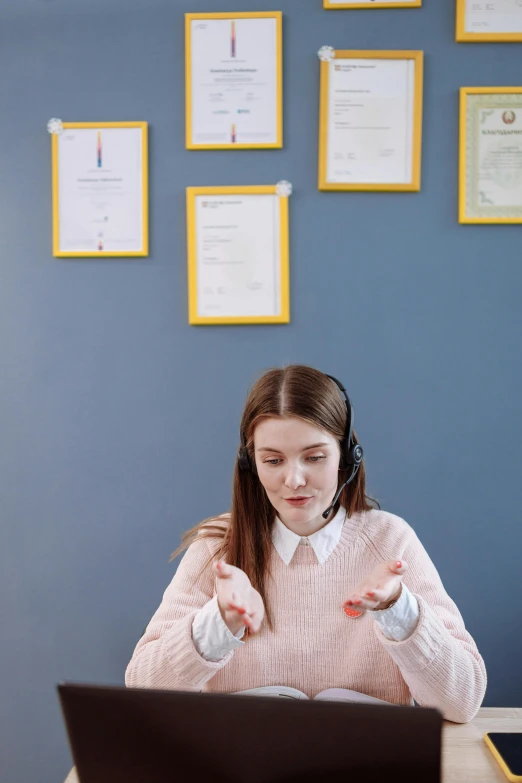 a woman sitting at a desk in front of a laptop, by Julia Pishtar, trending on pexels, academic art, wearing headset, standing in class, pastel', calmly conversing 8k