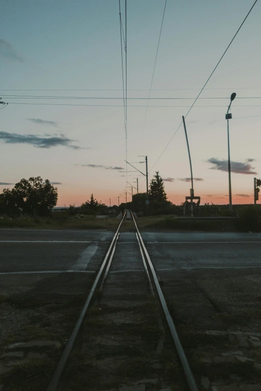 a couple of train tracks sitting next to each other, by Attila Meszlenyi, unsplash, realism, dusk sky, suburb, low quality photo, panoramic photography