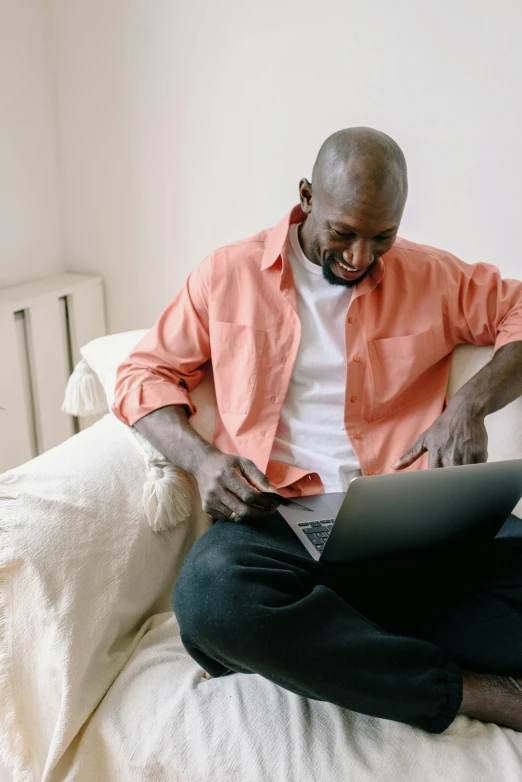 a man is on a bed typing on his laptop