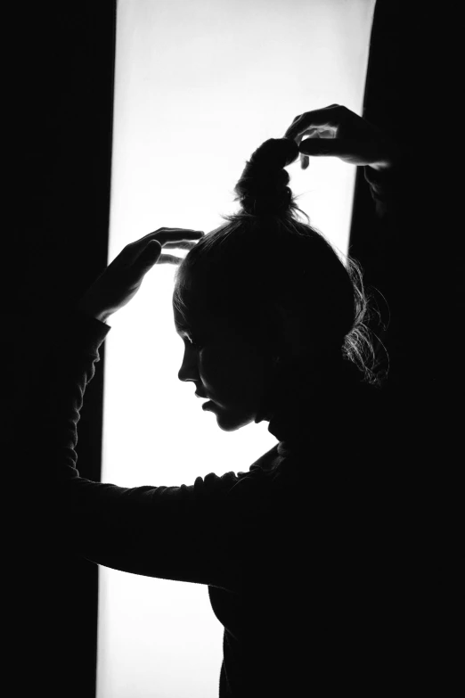 a black and white photo of a woman brushing her hair, a black and white photo, trending on pexels, romanticism, siluette, back - lit, sadness, her hair pinned up