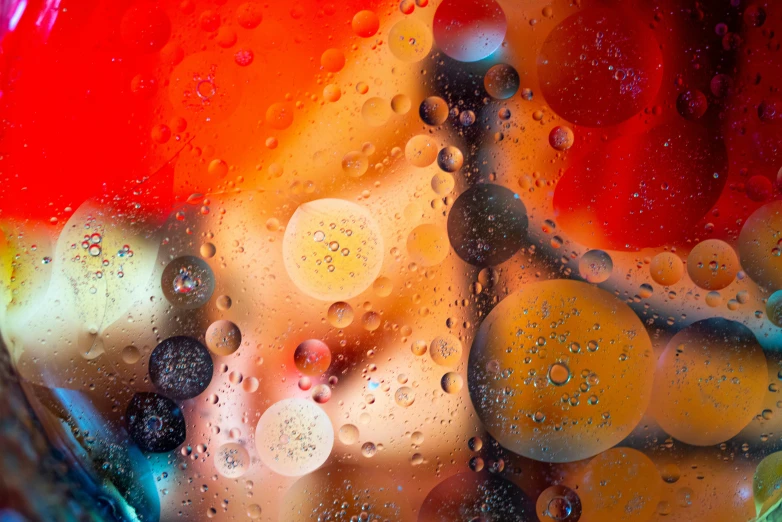 a close up of a glass filled with liquid, a microscopic photo, by Jan Rustem, abstract art, floating planets and moons, red orange blue beige, droplets on the walls, vibrant colours