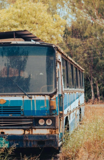 a bus that is sitting in the grass, by Lee Loughridge, unsplash, burnt umber and blue, photo of poor condition, australian, 1996)
