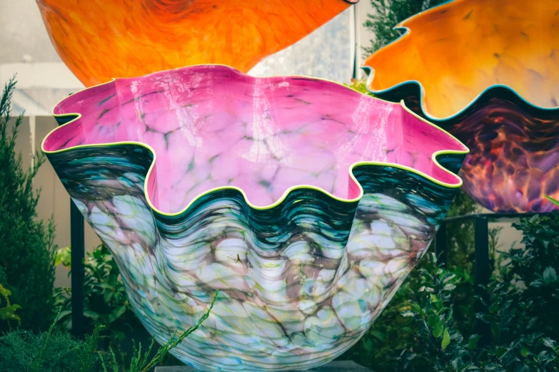 a colorful sculpture sitting on top of a lush green field, an abstract sculpture, by Meredith Dillman, unsplash, chihuly, bowl, translucent gills, pink and orange