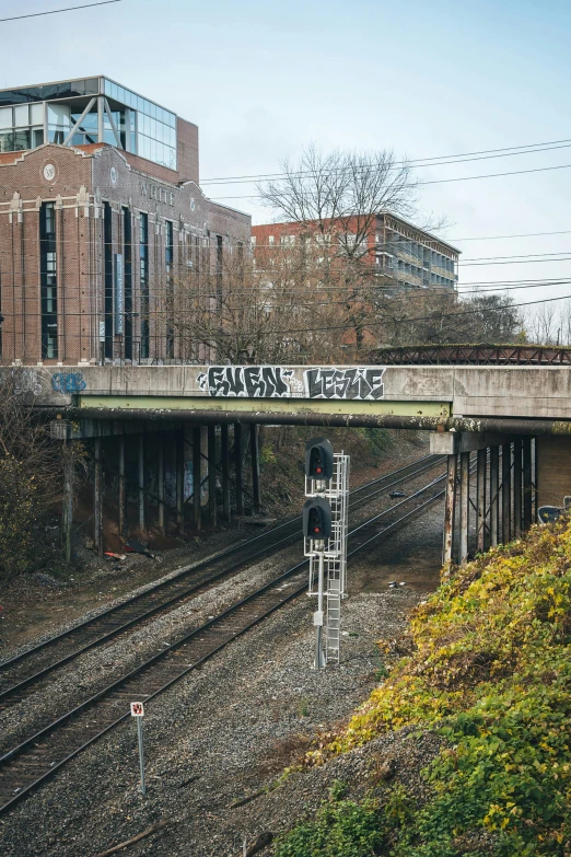 a train traveling down train tracks next to a tall building, inspired by Washington Allston, unsplash, graffiti, old bridge, instagram story, an eerie, taken in the early 2020s