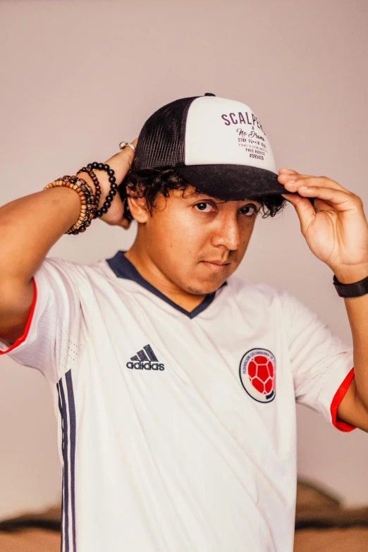 a man in a baseball hat stands with his hands on his ears