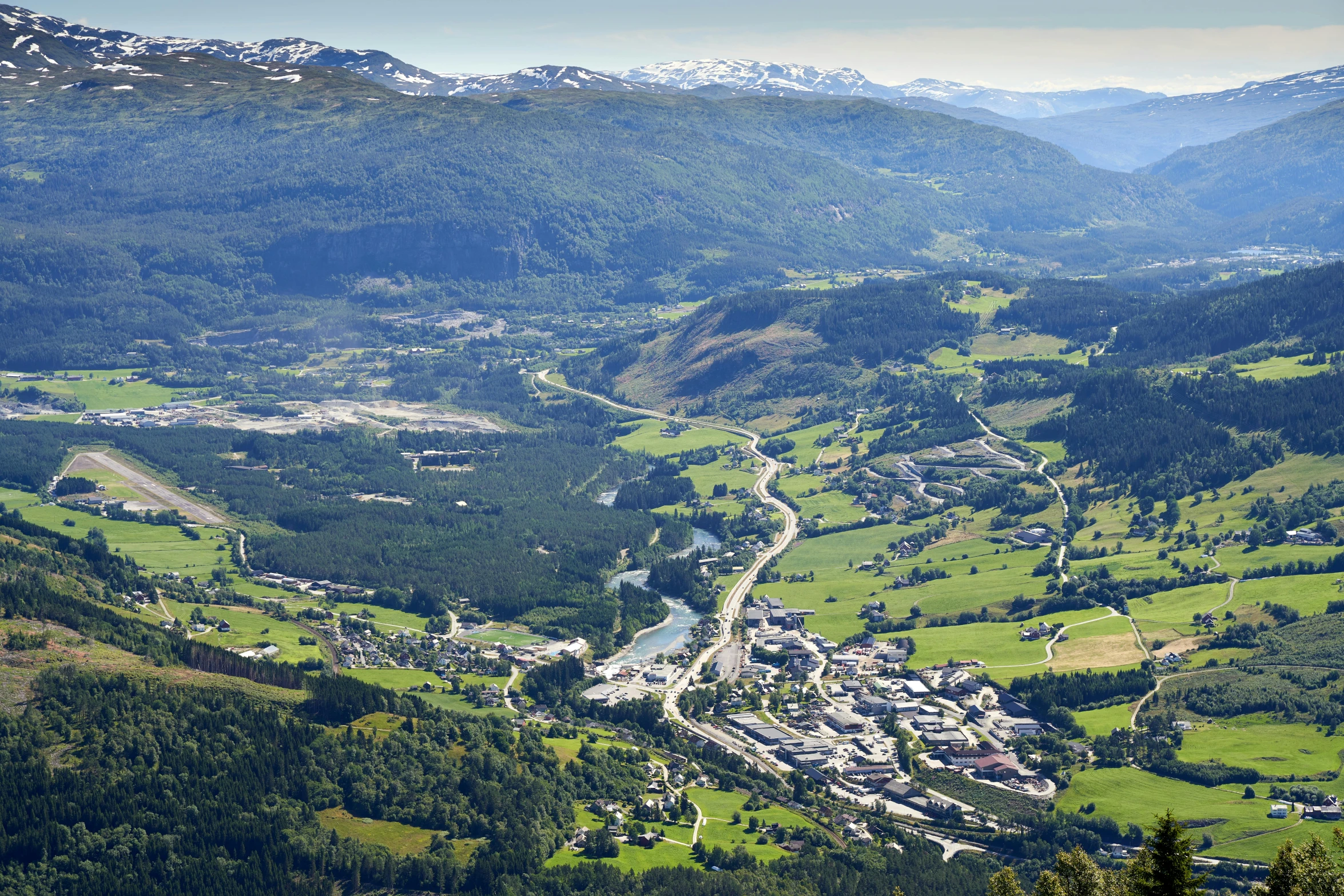 an aerial view of some green mountains with a small town on the right