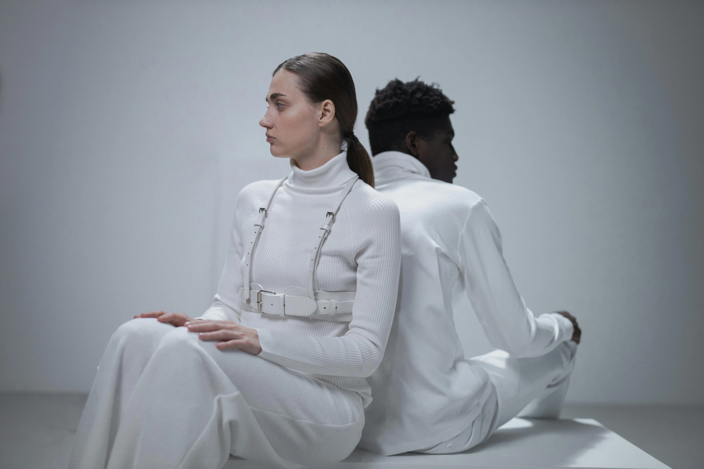 a man and a woman sitting next to each other, an album cover, inspired by Vanessa Beecroft, pexels contest winner, bauhaus, diverse medical cybersuits, white outfit, fashion shoot 8k, wearing turtleneck