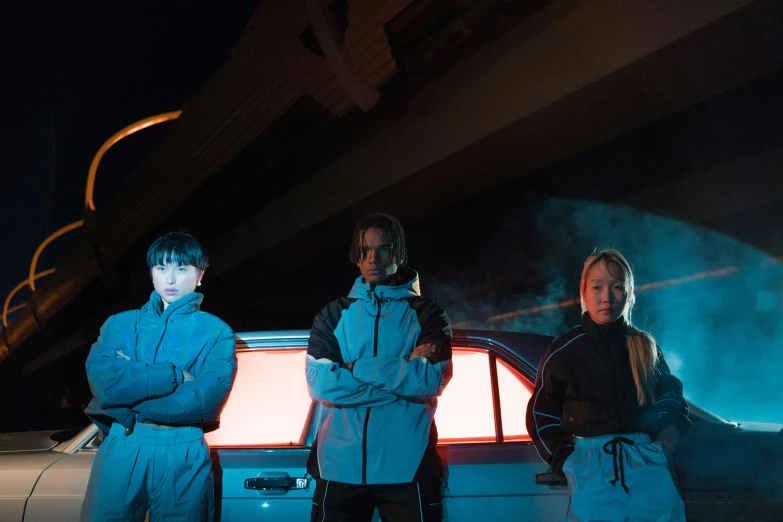 a group of people standing next to a car, inspired by Zhu Da, unsplash, wearing space techwear, orange and cyan lighting, grey, wearing a turtleneck and jacket