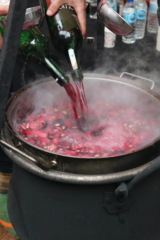 a person is pouring some red liquid in a pot