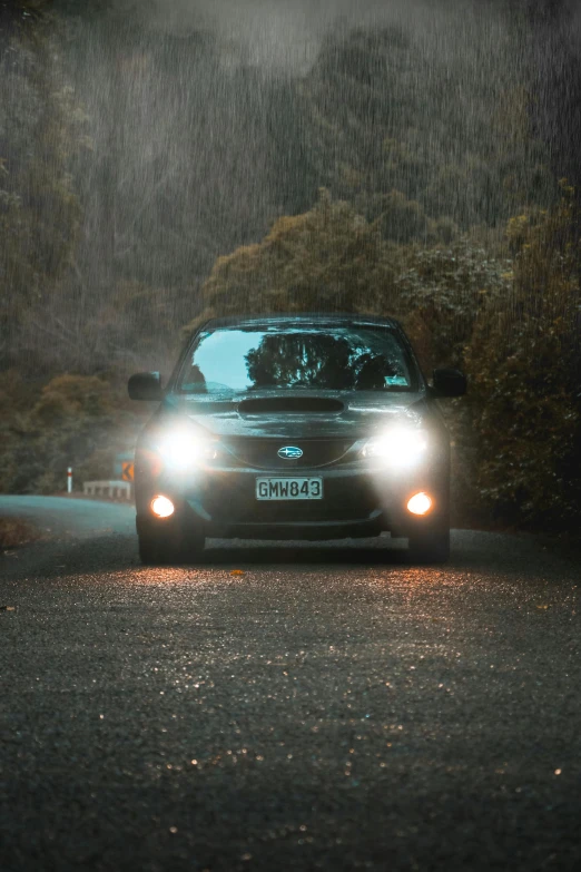 a grey compact car driving in the rain