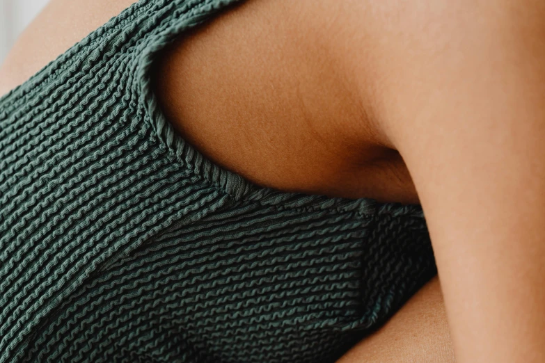 a close up of a person wearing a green top, by Carey Morris, trending on pexels, tanned body, crochet skin, dark teal, close-up product photo