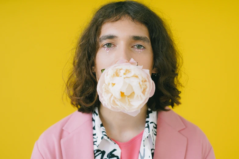 a man with a flower in his mouth, an album cover, trending on pexels, robert sheehan, milk bar magazine, pink and yellow, alexandros pyromallis