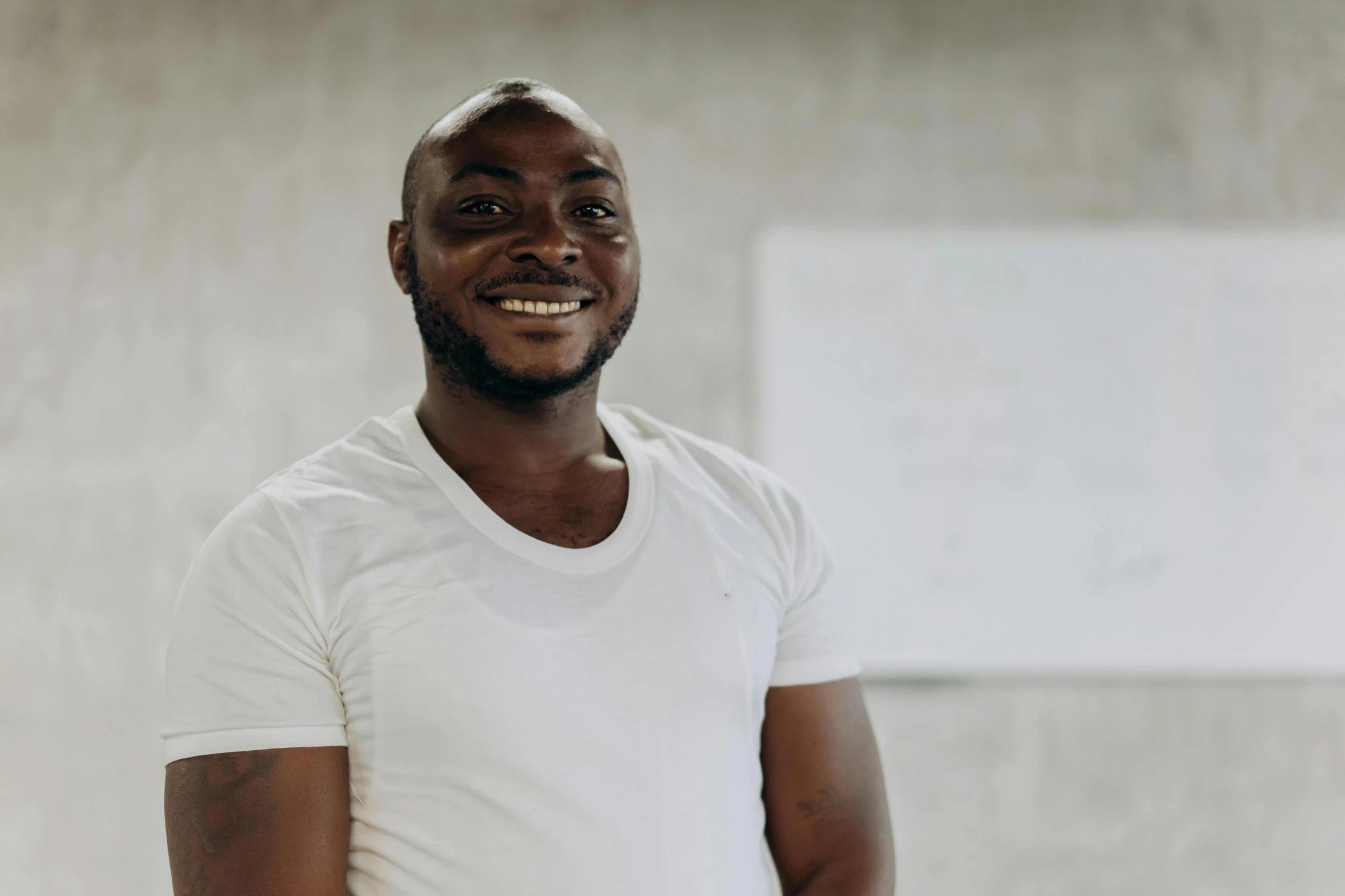 a man wearing a white shirt smiling while wearing his white pants