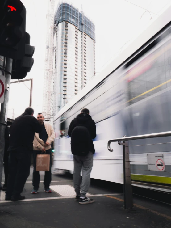 a group of people waiting at a bus stop, by Carey Morris, trending on unsplash, north melbourne street, charging through city, high rises, video still