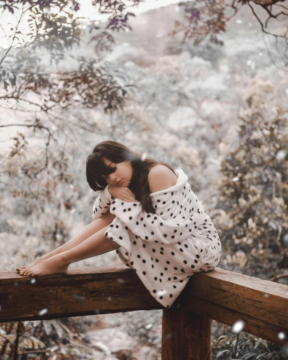 a woman sitting on top of a wooden fence, inspired by Elsa Bleda, trending on pexels, happening, polka dot, snowing outside, wearing a white dress, sitting on a mocha-colored table