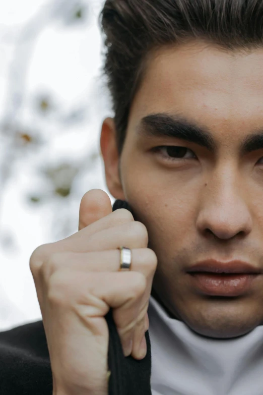 a man wearing a silver ring holding a black object