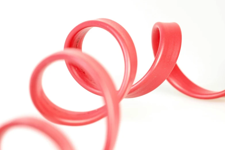 a pair of red rubber springs on a white surface, by Doug Ohlson, gigantic pink ringlets, zoomed in, 3 d print, ribbon