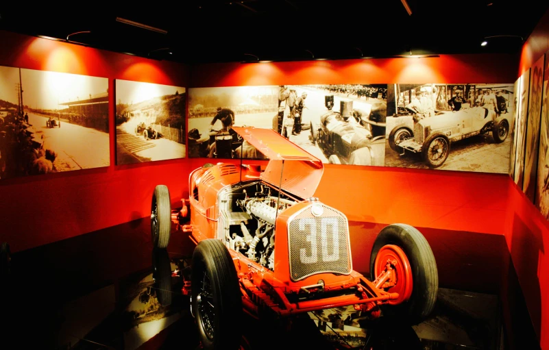 an old race car on display in a museum, pexels contest winner, red atmosphere, roaring twenties, on a racetrack, graphic”