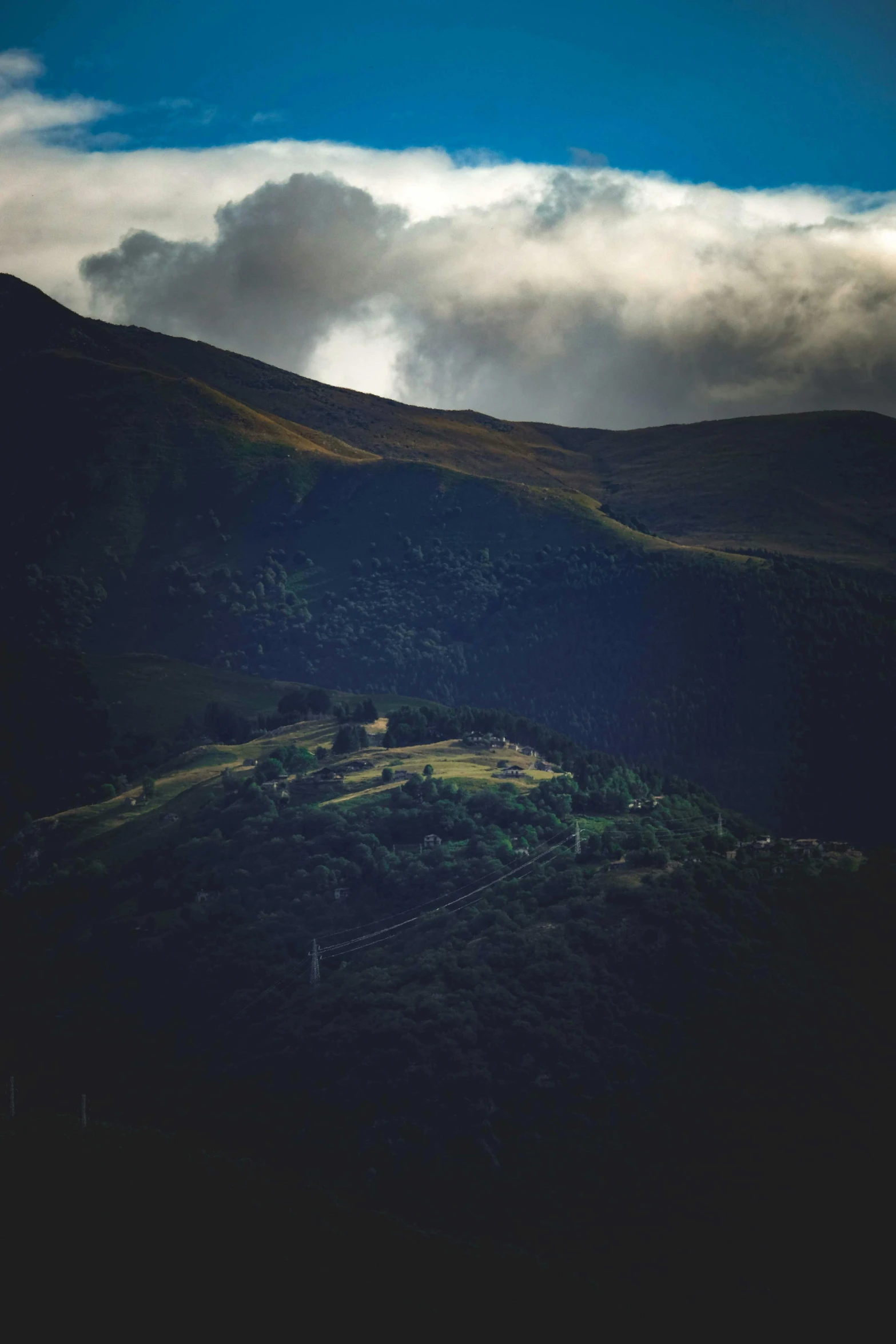 green hillside with dark clouds in background