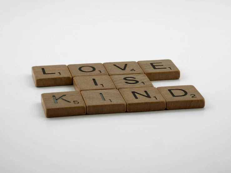 wooden scrabbles spelling love is kind on a white background, inspired by Ian Hamilton Finlay, light brown, brown, kubrick, press