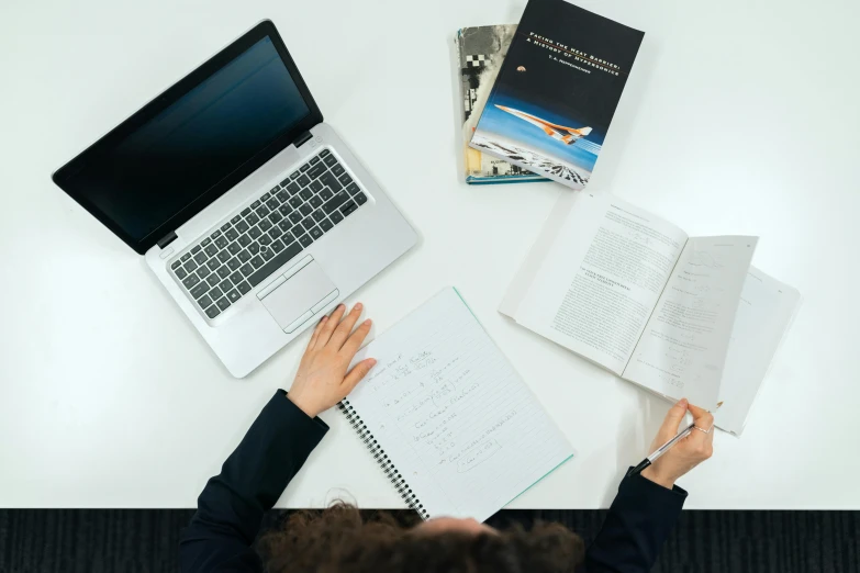 a person sitting at a table with a laptop and books, on medium grade paper, computer science, business surrounding, thumbnail