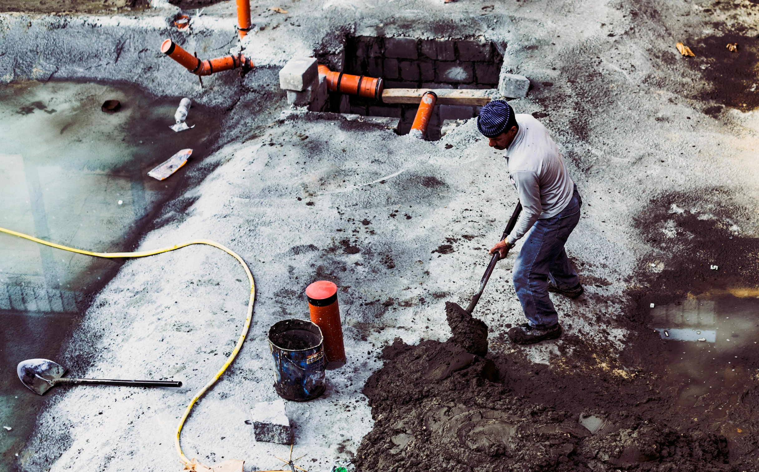 a man that is standing in the dirt, sewer, bright construction materials, working, background image