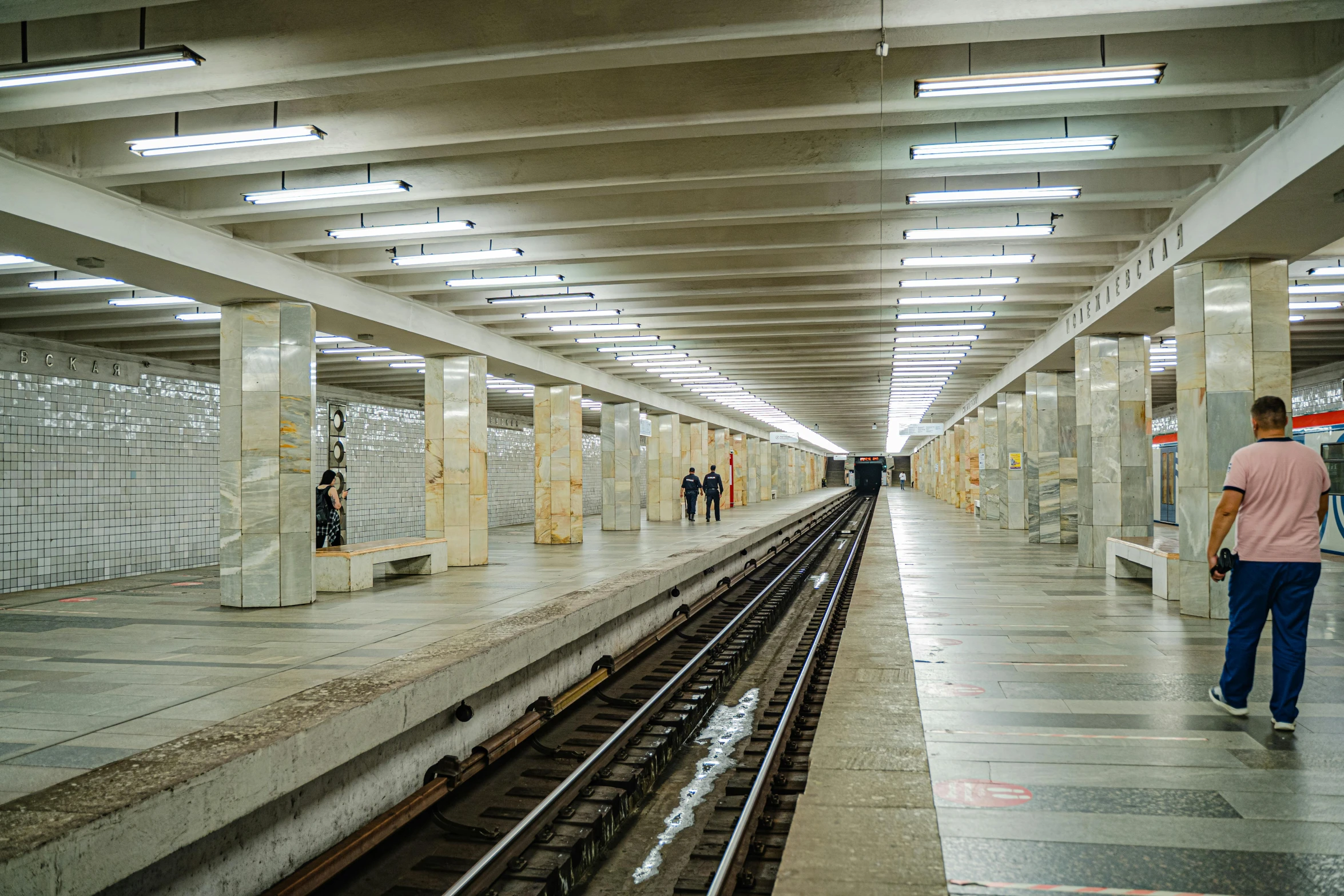 a train station with people walking on the tracks, by Mathias Kollros, unsplash, hyperrealism, underground metro, soviet brutalism, square, white