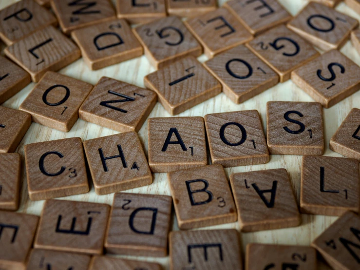 a pile of scrabbles sitting on top of a table, by Emma Andijewska, trending on unsplash, letterism, chaos is visible, explode and chaos, a wooden, looking across the shoulder