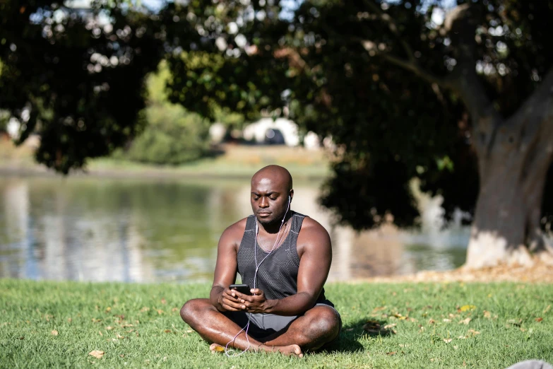 a man in a black shirt is meditating near a river