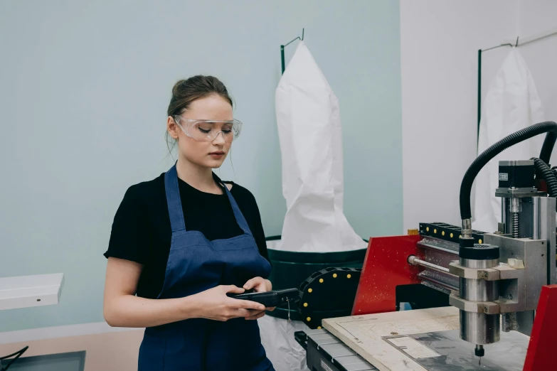 a woman standing in front of a machine, a silk screen, by Lee Loughridge, pexels contest winner, wearing an apron, 3 d modelling, metal readymade, profile image