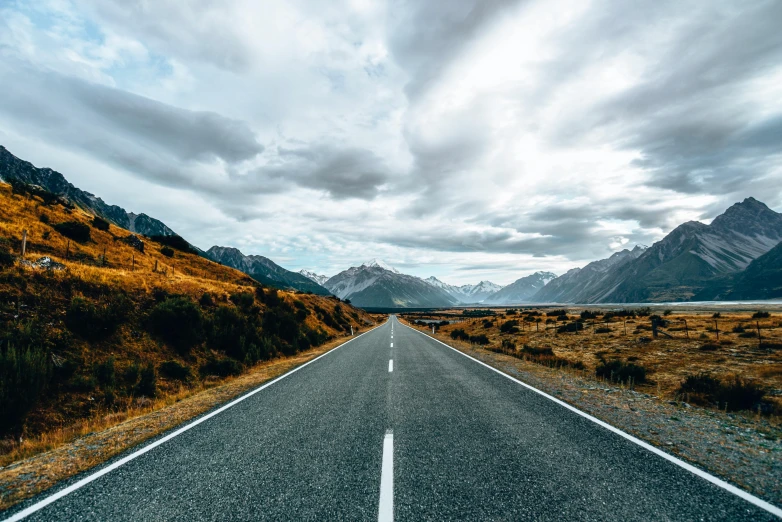 an empty road with mountains in the background, an album cover, unsplash contest winner, new zealand, 🚿🗝📝