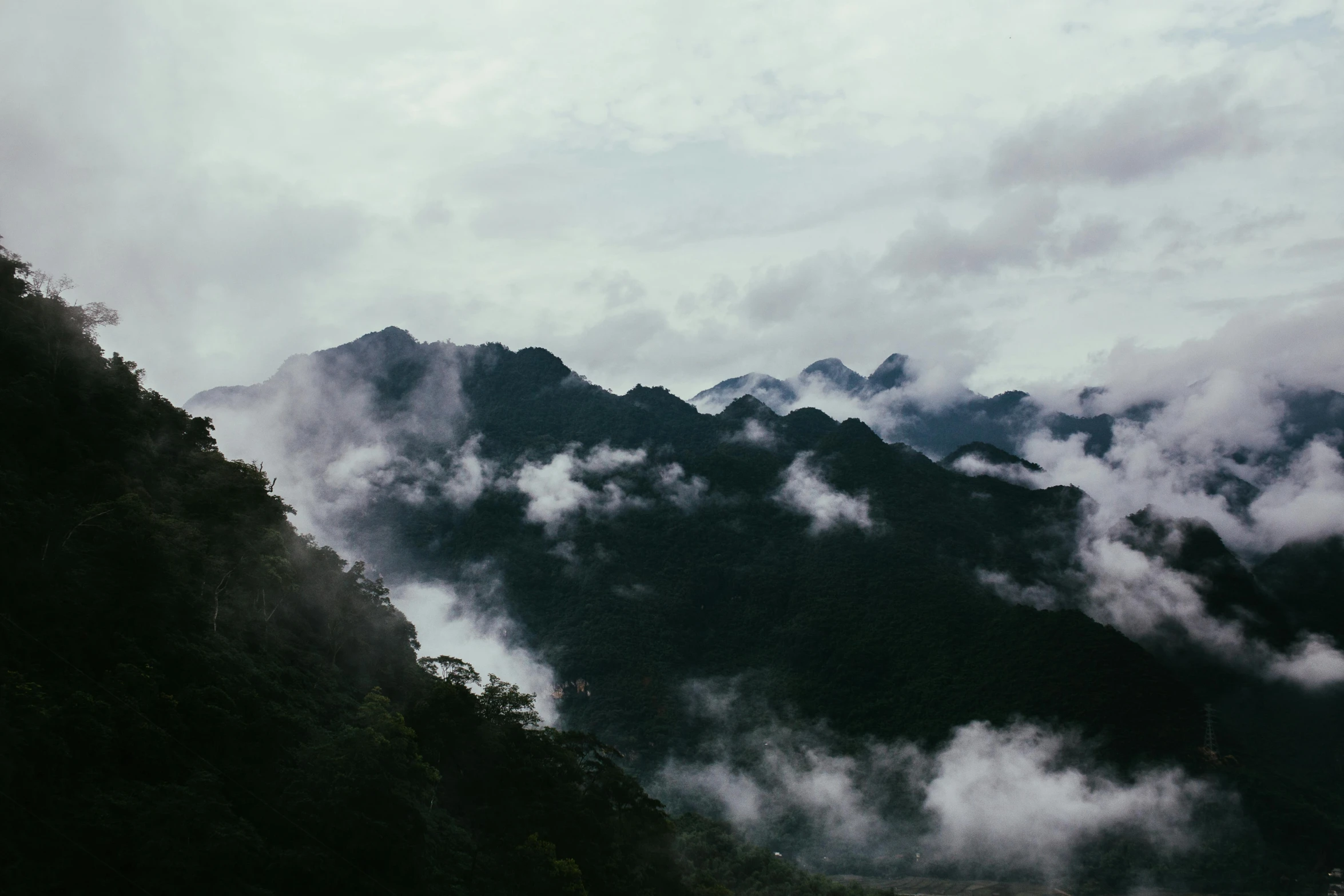 a cloudy valley with mountains on the far side