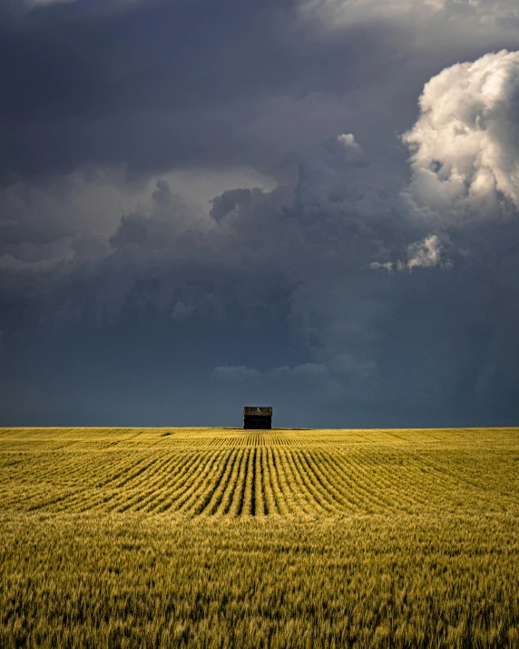 a field with a house in the middle of it, a picture, unsplash contest winner, land art, storm on horizon, taken in the late 2010s, colour photography, 4 0 0 mm