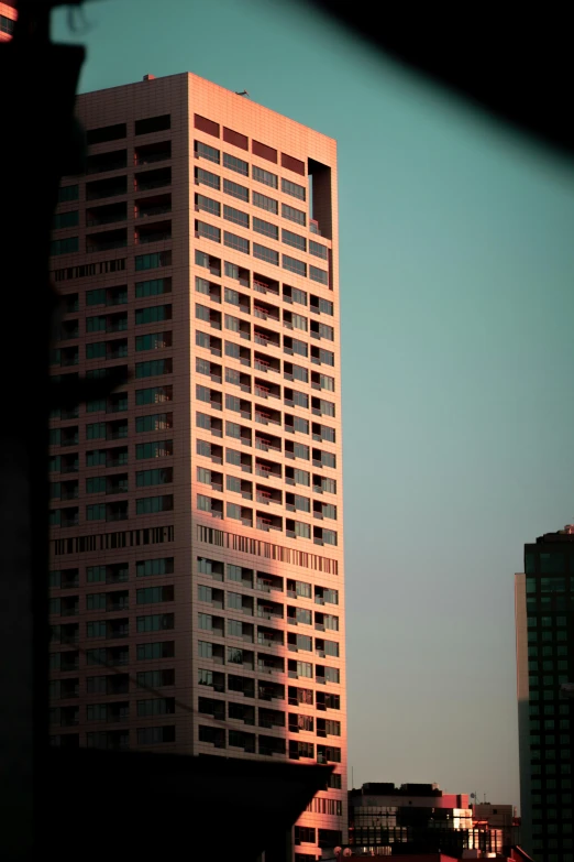 a tall building sitting in the middle of a city, a picture, inspired by Elsa Bleda, minimalism, pink and teal, late afternoon light, 8 0 mm photo, taken in the late 2010s