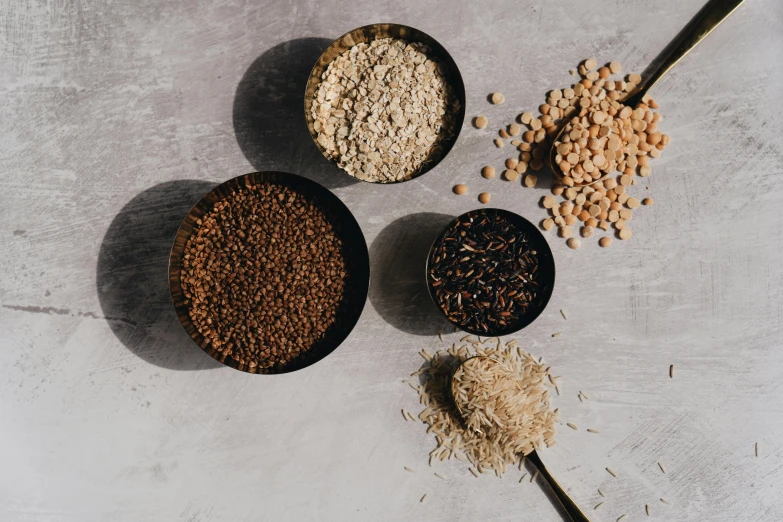 a table topped with bowls filled with different types of cereal, a portrait, pexels, renaissance, background image, rice, on a gray background, gravels around