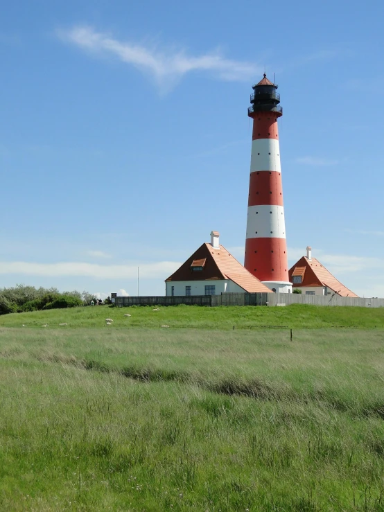 a lighthouse next to a farm on a sunny day