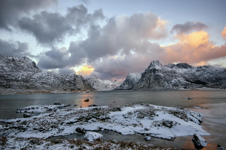 a snow covered lake with large mountains in the background