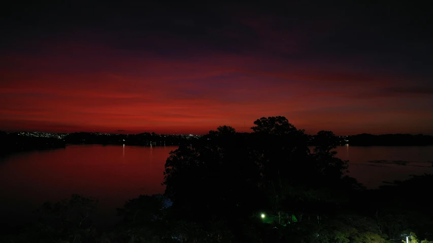 a large body of water next to a forest, by Joseph Severn, pexels contest winner, hurufiyya, blood red colored sky, scenic view at night, sunset panorama, humid evening