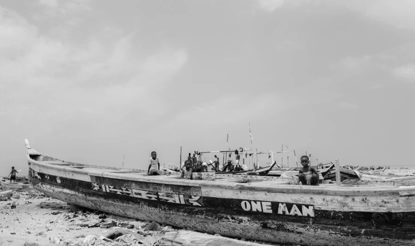 a black and white photo of a boat on the beach, unsplash, men, surrounding the city, mami wata, on a bright day