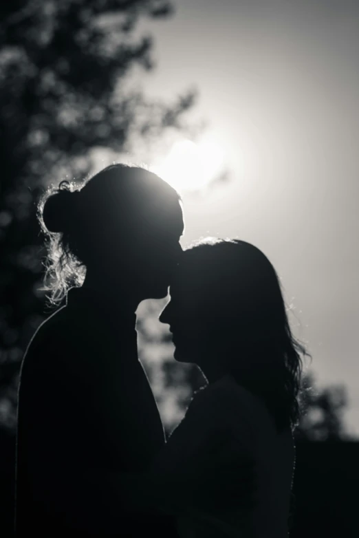 a silhouette of a couple kissing in front of the sun, a black and white photo, pexels contest winner, portrait of two girls kissing, instagram post, profile shot, lesbian