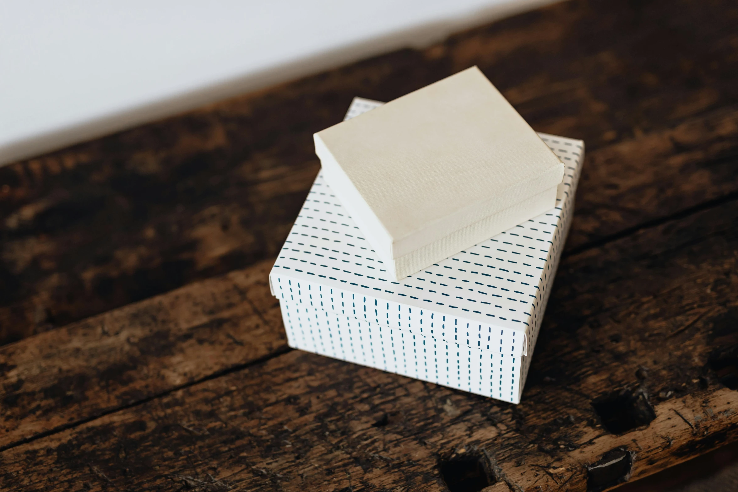 a stack of white boxes sitting on top of a wooden table, a stipple, by Helen Stevenson, unsplash, private press, carved soap, polka dot, indigo, square lines