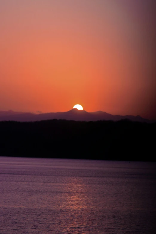 the sun is setting over a large body of water, by Doug Ohlson, sun rises between two mountains, photograph, suns