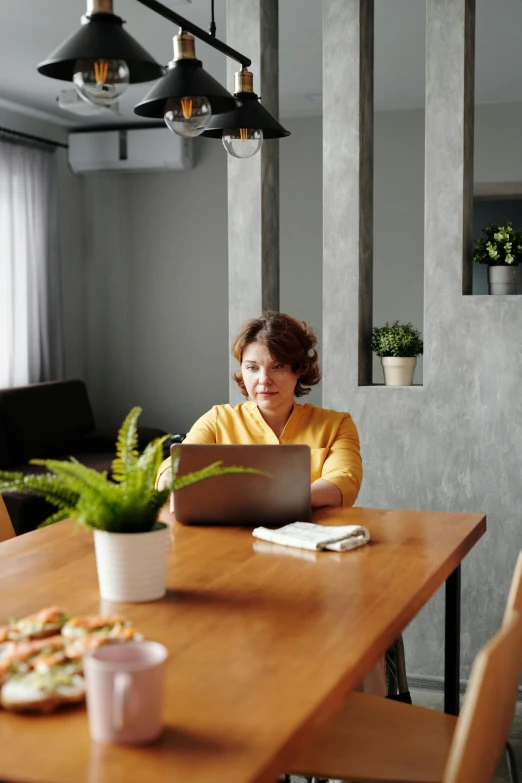 a woman sitting at a table with a laptop